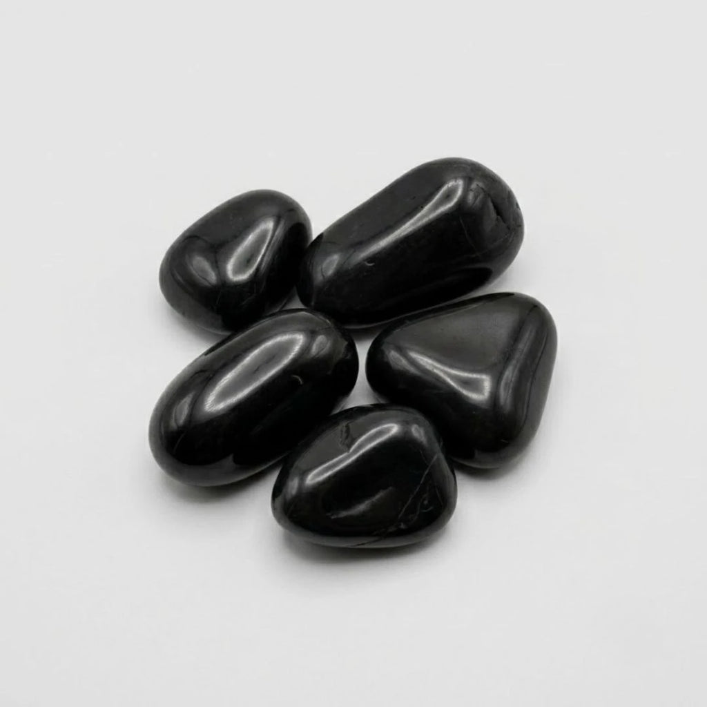 Five smooth, high gloss polished black pebbles arranged in a small cluster on a light gray background.