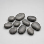 Nine smooth, polished black stones arranged in a loose cluster on a light gray background.