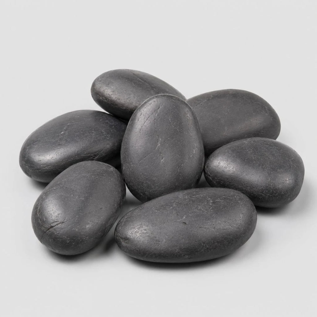 A pile of smooth, black polished pebbles stones on a light gray background.