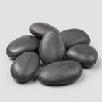 A pile of smooth, black polished pebbles stones on a light gray background.