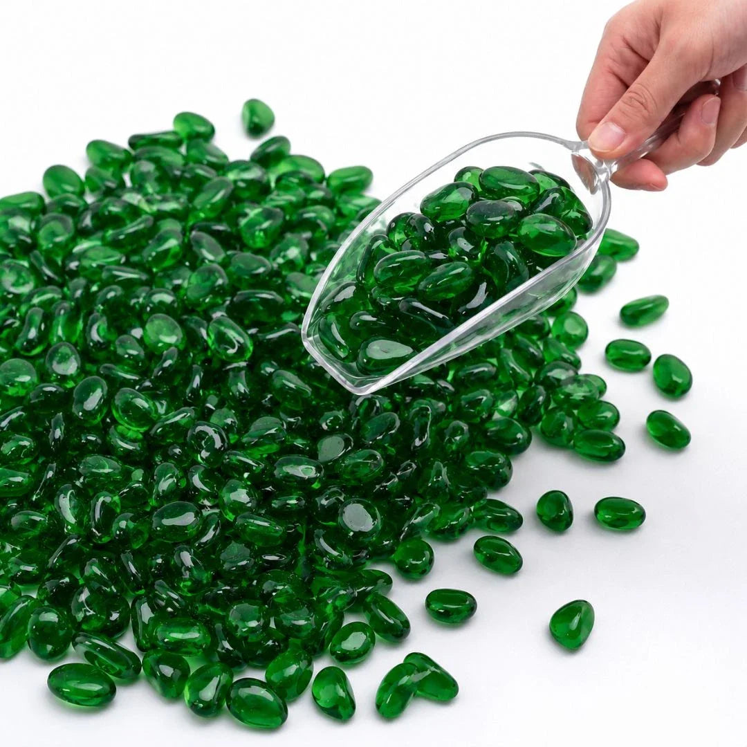 Hand holding a scoop of glossy green glass stones on a white background.