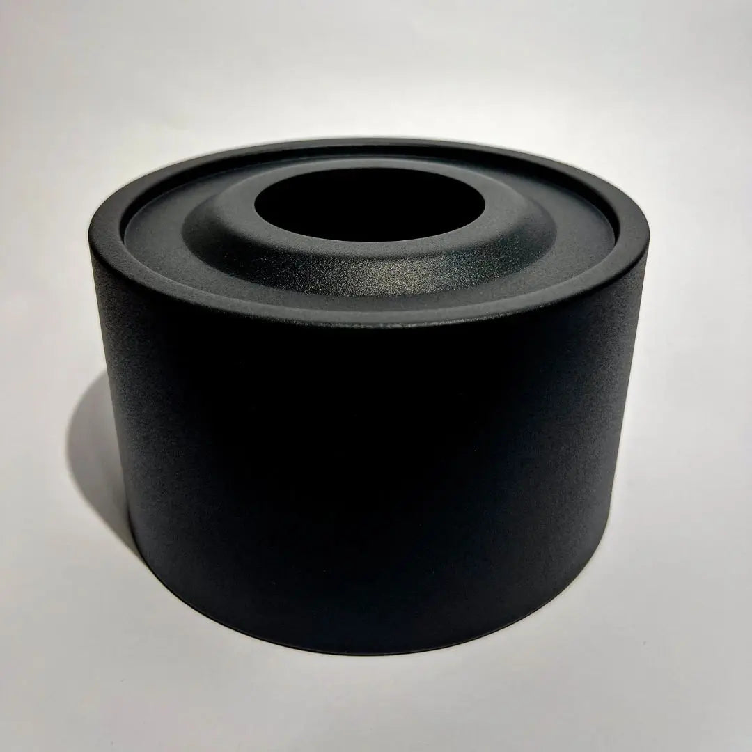 Black metal tabletop fireplace with a cylindrical design on a light background.