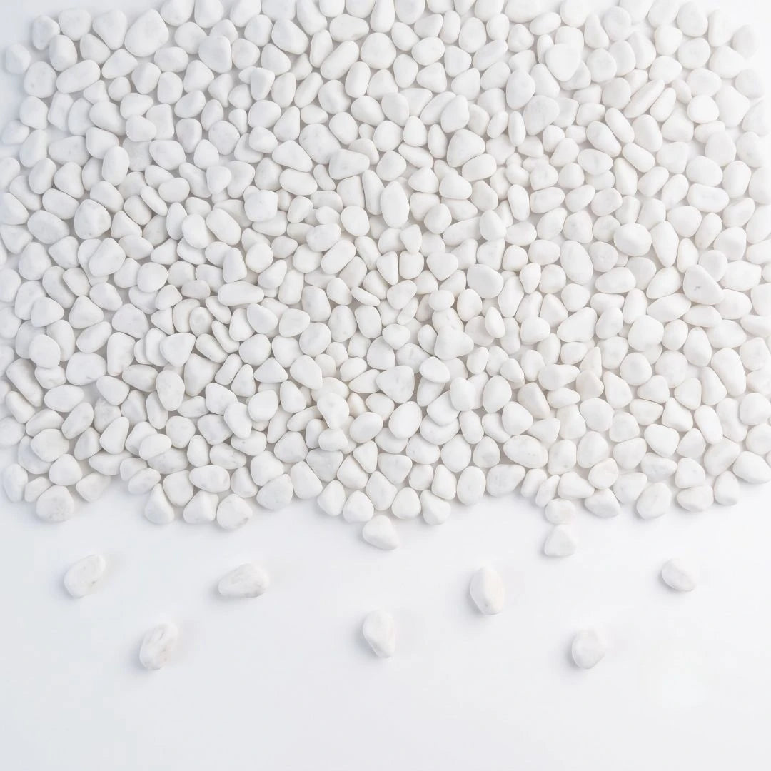 White decorative pebbles scattered across a white background, with a few stones lying on the surface in front of the pile.