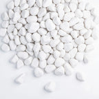 White decorative pebbles piled on a clean white background, with a few scattered around the bottom.