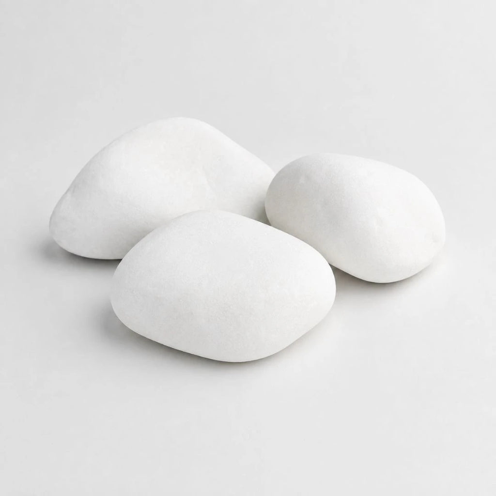A pile of smooth, rounded white decorative stones in largest size cobbles on a plain light gray background.