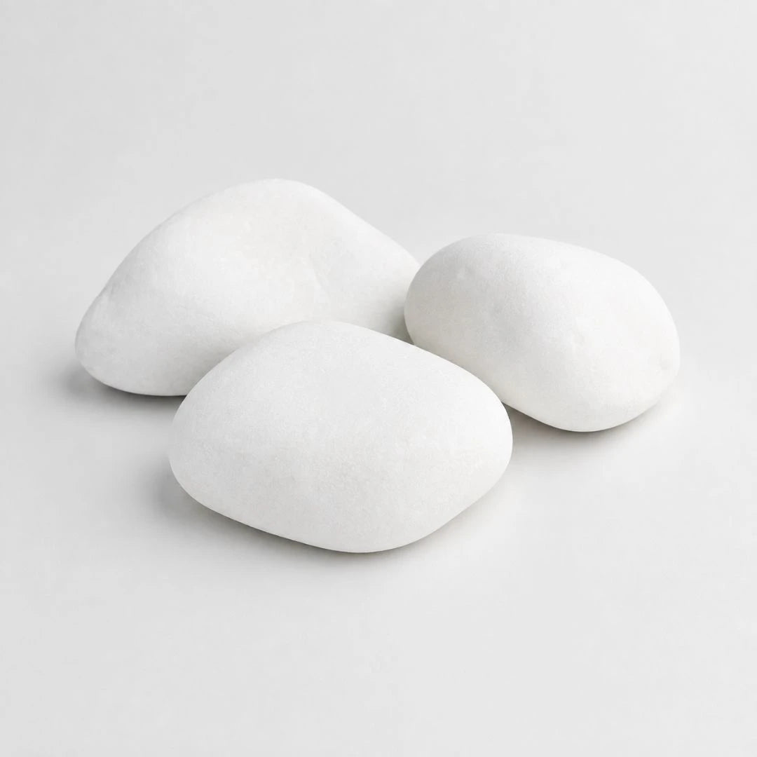 A pile of smooth, rounded white decorative stones in largest size cobbles on a plain light gray background.